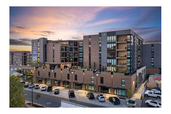 A modern multi-story building with a parking lot in front.